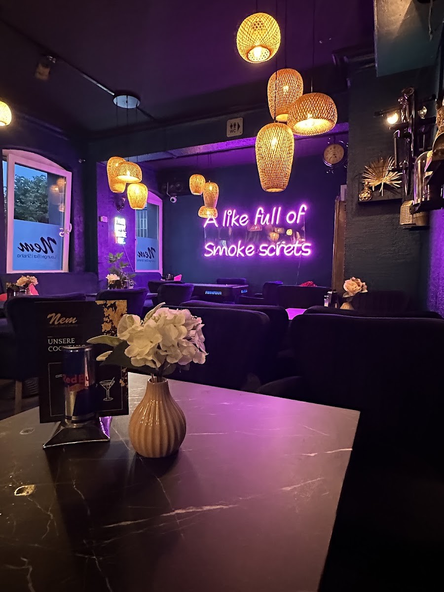 Gemütlicher Tisch in der Nem Lounge mit Blumendeko und Cocktailkarte